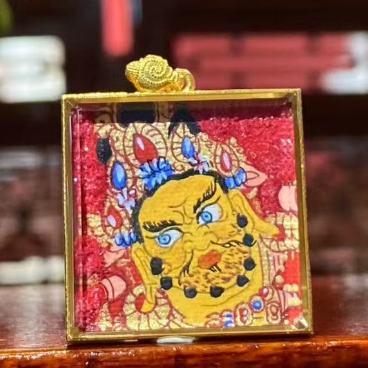Hand-painted Yellow Jambhala mini Thangka pendant featuring a bold expression and red background, housed in an 18K gold Gau box