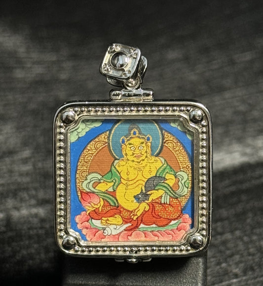 Front view of Yellow Jambhala mini thangka pendant featuring hand-painted Rebgong thangka art with natural mineral pigments inside a silver pendant frame
