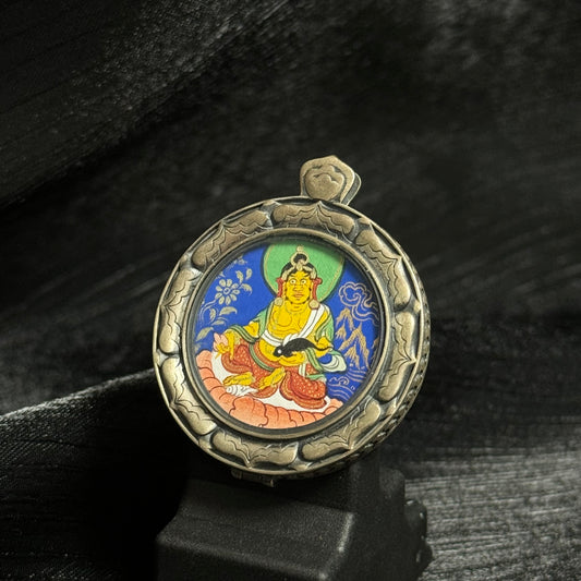 Front view of a Yellow Jambhala mini thangka pendant hand-painted with mineral pigments in the Rebgong style, set in a carved 925 silver protective frame.
