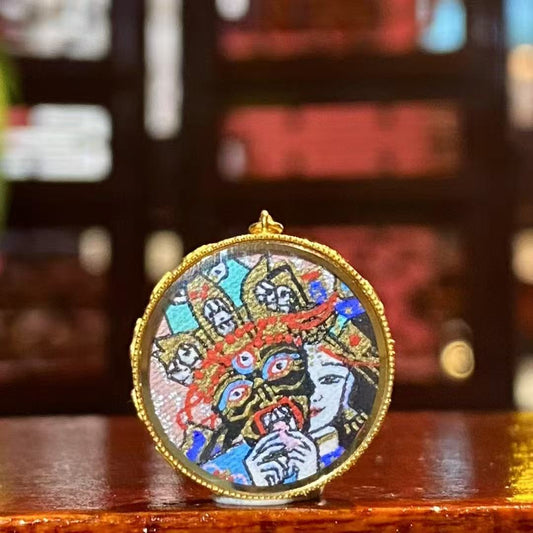 Front view of a round Tibetan Ghau Thangka pendant featuring Zaki Lham, hand-painted in 18K gold with Rebgong Thangka craftsmanship