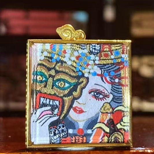 Front view of a hand-painted Zaki Lhamo thangka pendant depicting the Tibetan female wealth guardian, finished with gold detailing and set in an 18K gold gau box