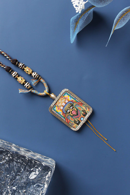 Front view of Zaki Lhamo, the Tibetan female wealth goddess, hand-painted with layered gold powder by Rebgong lama artists, set in a finely crafted 925 silver frame with traditional braided cord necklace