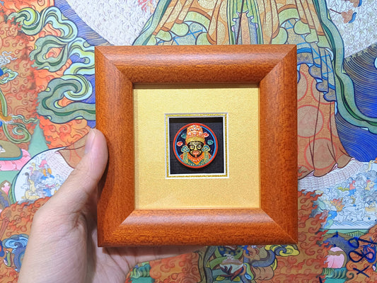 Hand-held view of Zaki Ram mini tsa-tsa thangka desk shrine showing framed devotional artwork with mineral pigment painting