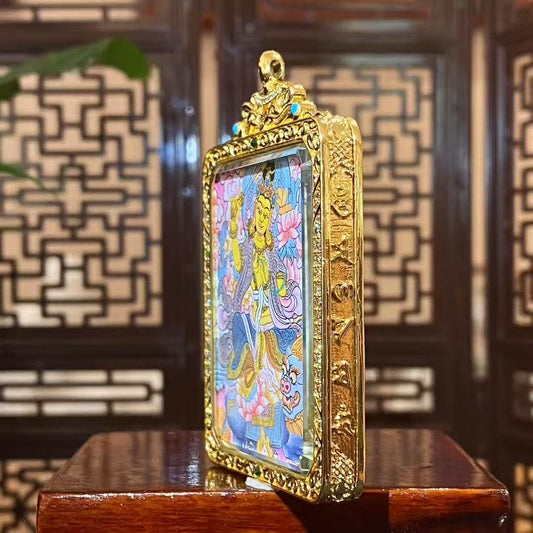 Gold-plated copper Ghau pendant with handcrafted details, framing a traditional Tibetan thangka