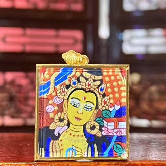 Front view of a double-sided Manjushri Bodhisattva mini thangka pendant, hand-painted and set in an 18K gold Gau box with sapphire crystal glass