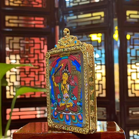 Side view of a double-sided Manjushri Bodhisattva mini thangka pendant showing the ornate gold-plated copper Gau box frame