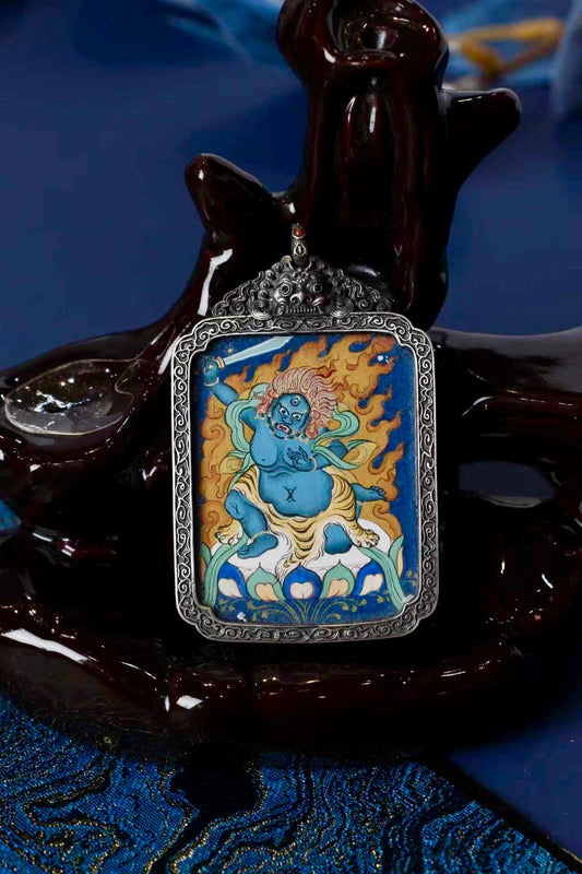 Close-up of an Acalanatha (Fudo Myo-o) mini thangka pendant, hand-painted in mineral pigments, set in an ornate antique silver case.