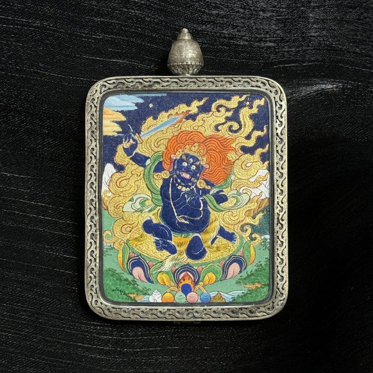 Detailed front view of Acalanatha thangka pendant with vibrant mineral pigment painting mounted inside a handcrafted silver pendant case