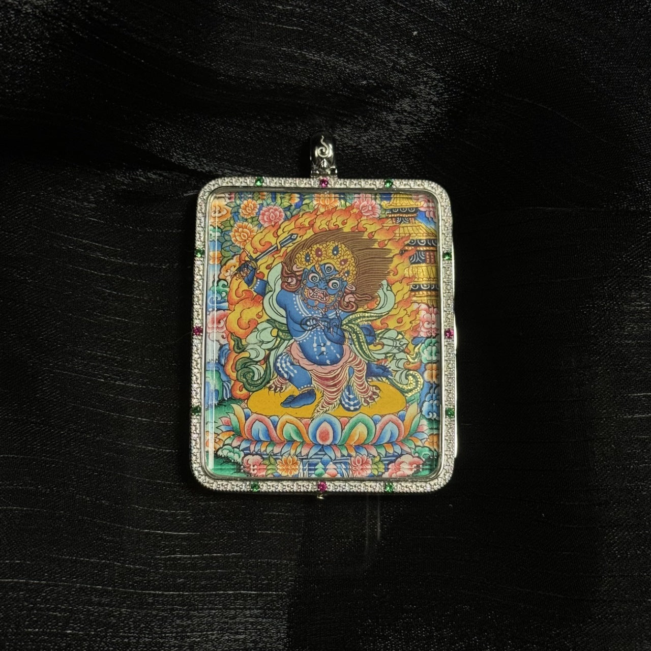 Front view of the Acalanatha mini thangka pendant showing the dynamic posture of Fudo Myo-o standing on a lotus base, surrounded by flame aureole and detailed traditional Tibetan decorative patterns.