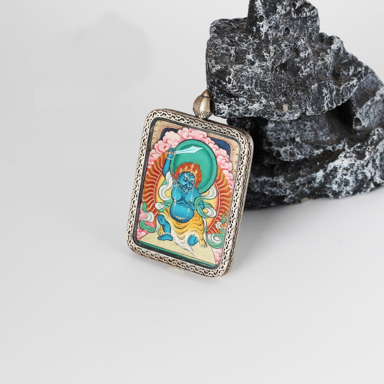 Side profile of Acalanatha mini Thangka pendant highlighting the thickness of the silver case, fine metal craftsmanship, and the mounted hand-painted Thangka artwork.