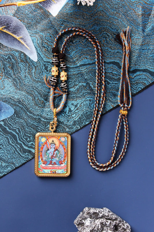 Full view of the Akasagarbha Bodhisattva mini thangka pendant showing the front painting, rectangular metal case, braided cord, bead section with patterned round beads, gold-tone spacer details, and the adjustable cord ends.