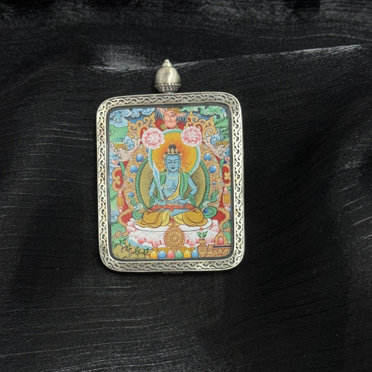 Front view of Akasagarbha Bodhisattva mini thangka pendant, hand-painted with mineral pigments, seated on lotus throne with halo, enclosed in Dunhuang Nine-Colored Deer silver gawu case with engraved border.