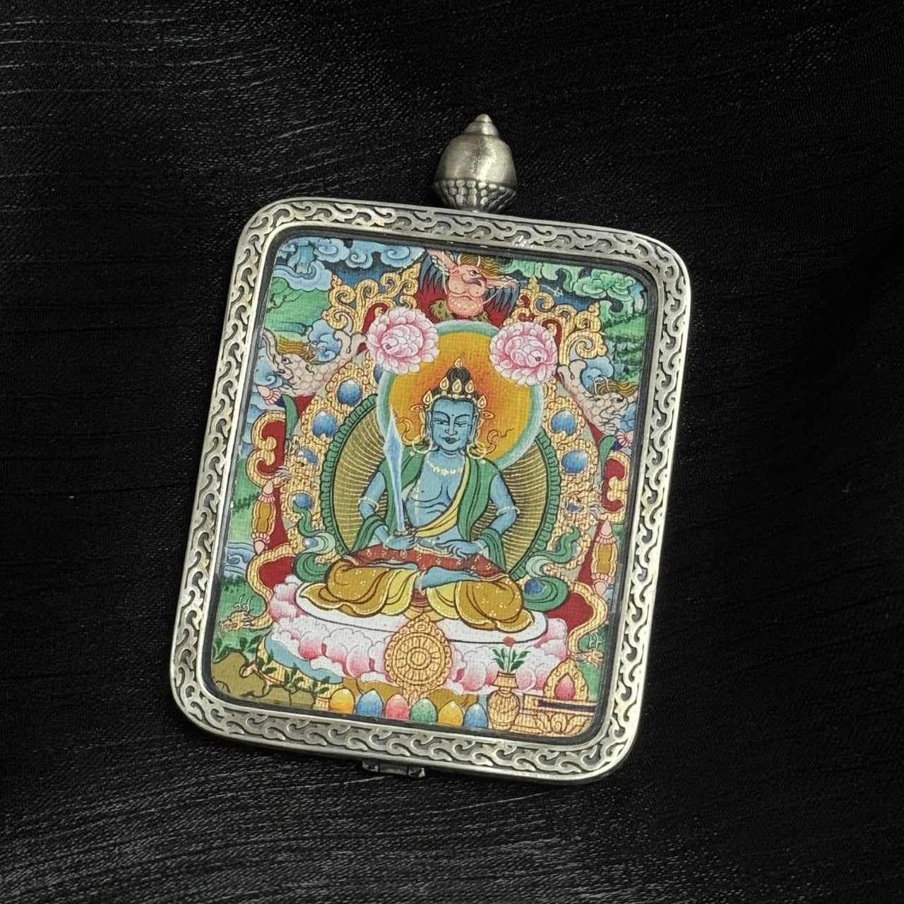 Side perspective of Akasagarbha Bodhisattva Tibetan Miansa mini thangka pendant emphasizing color saturation, halo structure, lotus throne, and engraved silver border craftsmanship.