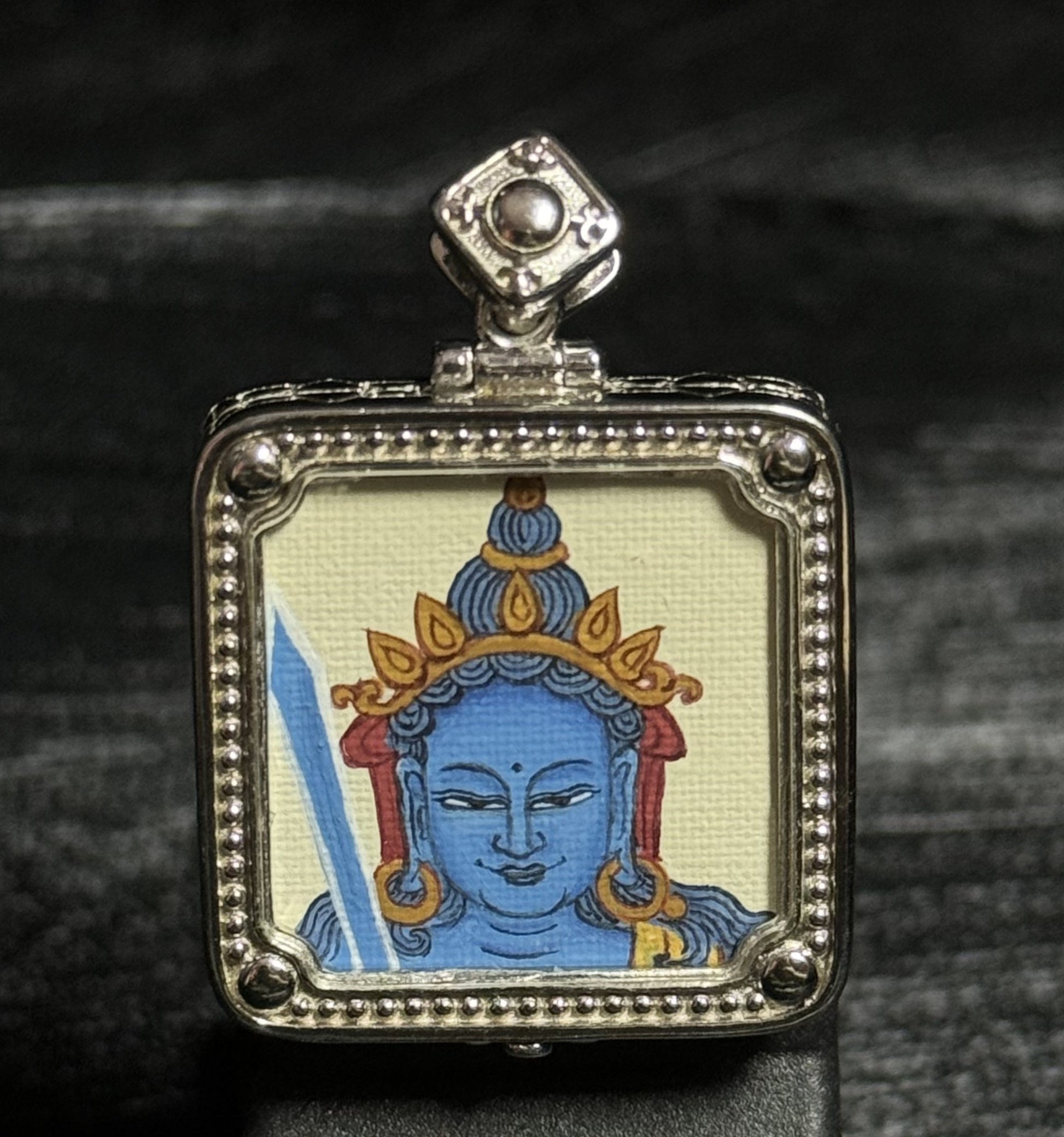 Front view of a hand-painted Akashagarbha Bodhisattva miniature thangka pendant painted with mineral pigments and mounted in a detailed 925 silver plated frame.