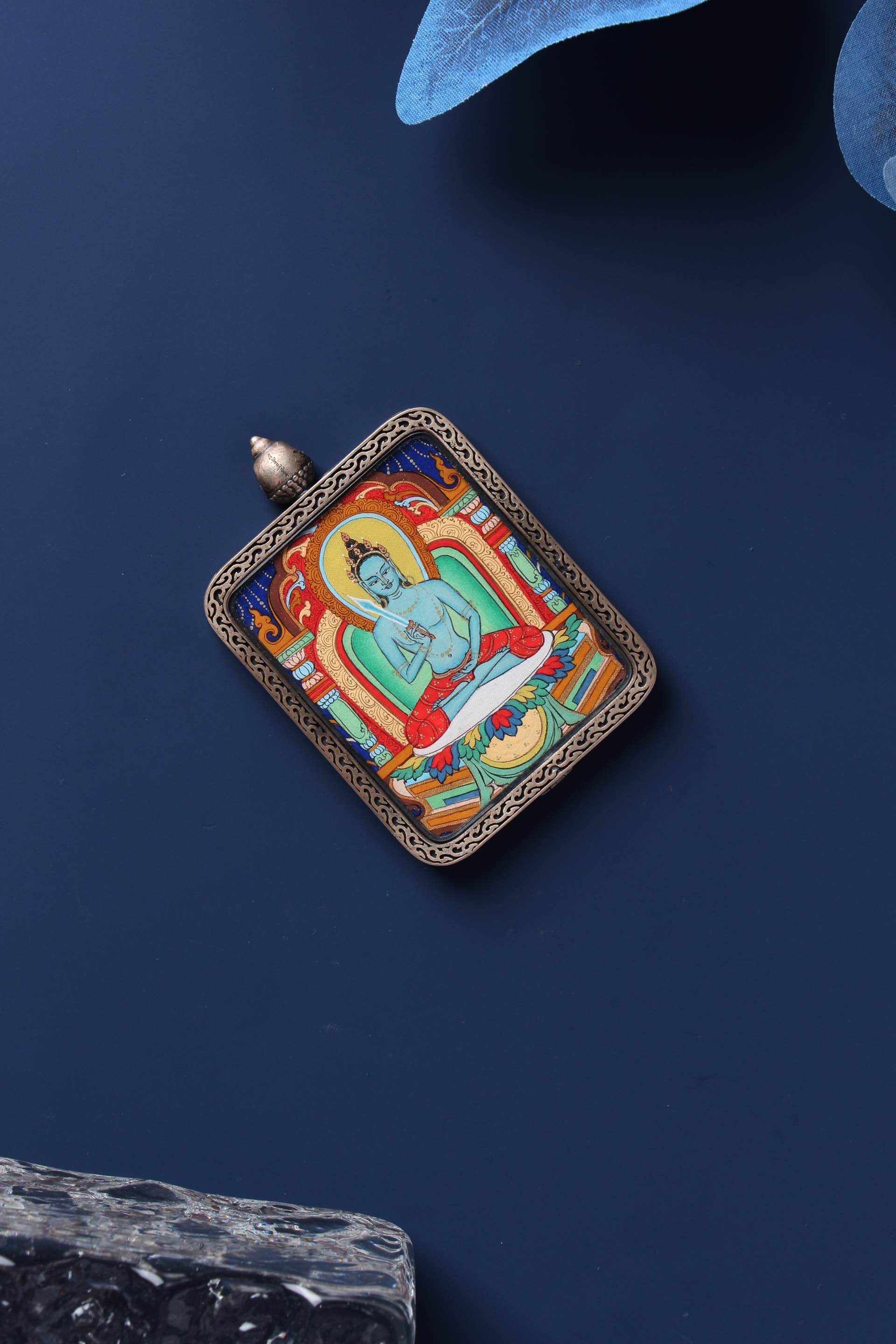Flat lay of a hand-painted Akashagarbha Bodhisattva mini thangka pendant in a Dunhuang Nine-Color Deer sterling silver case on a dark blue background