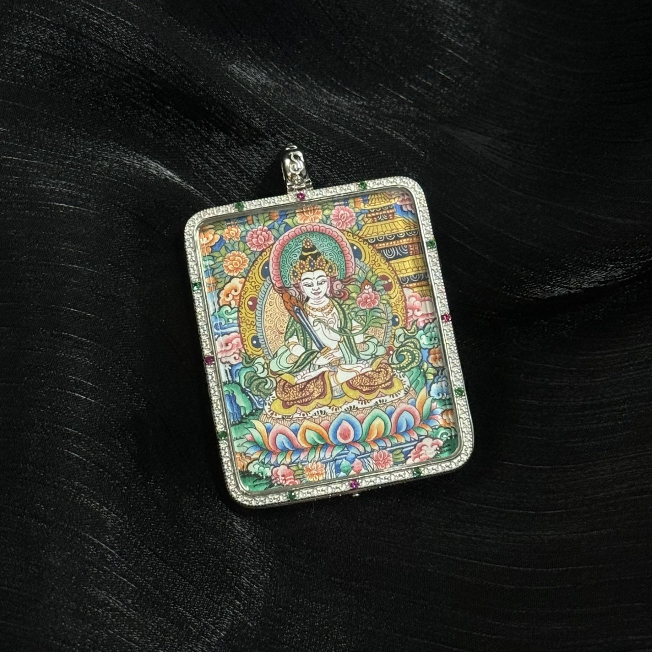 Front view of Akashagarbha Bodhisattva mini thangka pendant depicting the bodhisattva seated on a lotus throne with ornate halo, floral background, and detailed Tibetan decorative patterns.