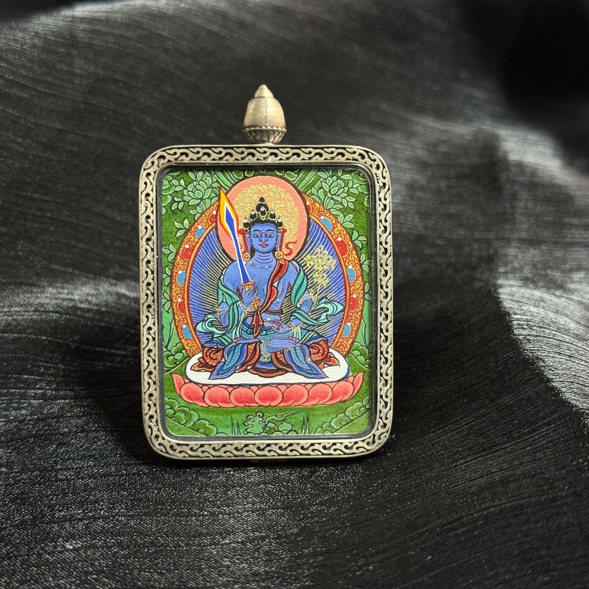 Front view of Akashagarbha Bodhisattva mini thangka pendant, hand-painted with natural mineral pigments in Rebgong style, featuring a detailed bodhisattva figure within an ornate silver pendant frame