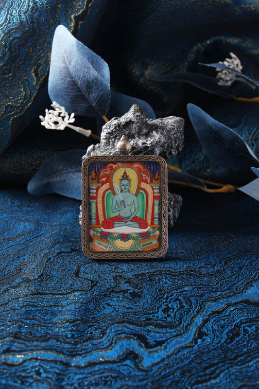 Hand-painted Akashagarbha Bodhisattva mini thangka pendant in a Dunhuang Nine-Color Deer sterling silver case, displayed on a blue textile background