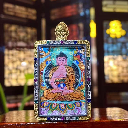 Front view of hand-painted Amitabha Buddha mini thangka in a gold-plated copper Gau pendant, featuring a seated Buddha with halo and detailed traditional iconography