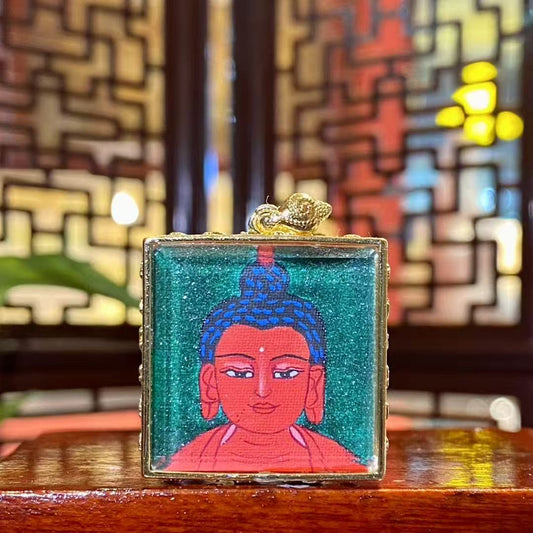 Front view of hand-painted Amitabha Buddha mini thangka in a gold-plated copper Gau pendant, featuring a serene Buddha portrait on a green background