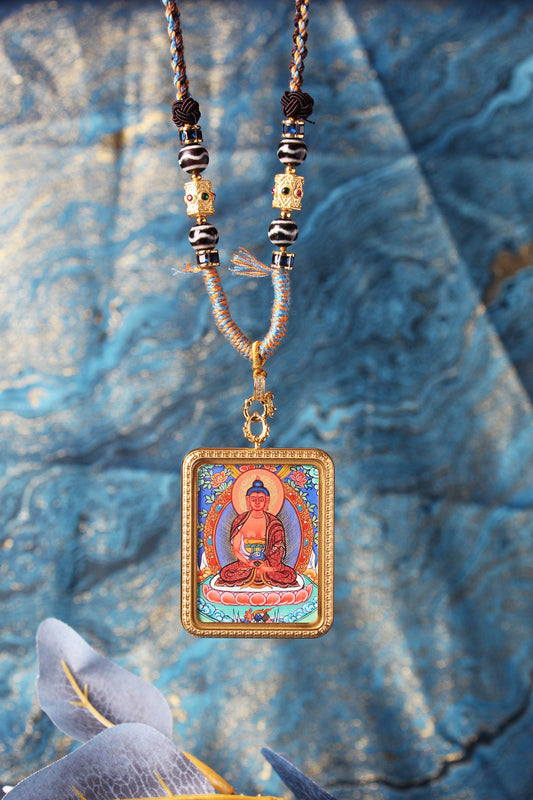 Close-up view of the Amitabha Buddha hand-painted mini thangka pendant, highlighting the serene Buddha image, lotus seat, mineral pigment colors, and detailed bead-and-knot cord craftsmanship.