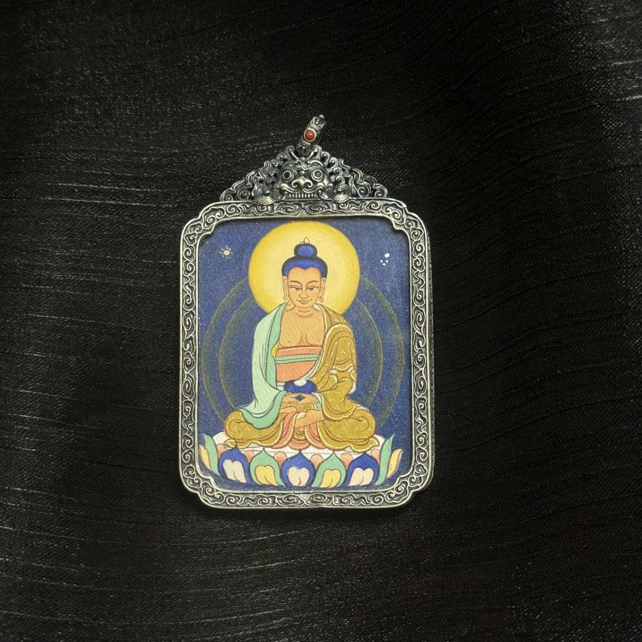 Front view of Amitabha Buddha mini thangka pendant, fully hand-painted with natural mineral pigments, set in a vintage-style silver case, Tibetan origin.