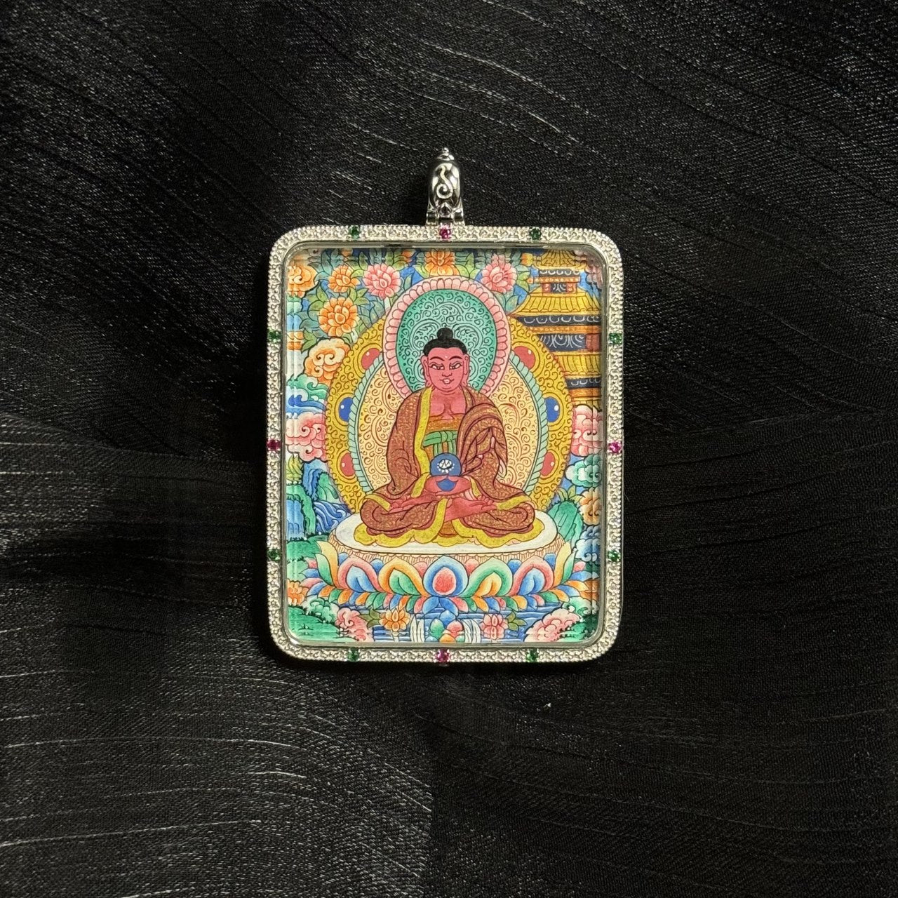 Miniature Amitabha Buddha thangka pendant artwork featuring traditional Tibetan iconography, lotus throne, halo, floral motifs, and detailed mineral pigment painting within a square devotional pendant.