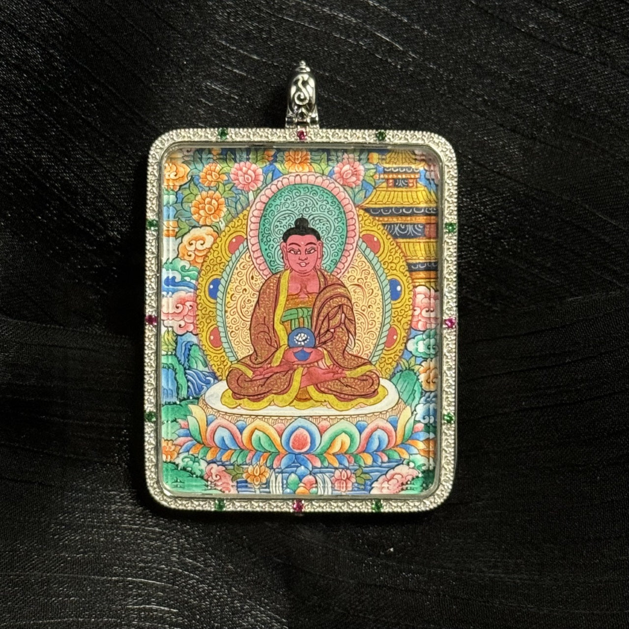 Detailed hand-painted Amitabha Buddha mini thangka pendant showing seated Buddha holding a ritual bowl on a lotus pedestal with intricate Tibetan background patterns and colorful mineral pigment painting.