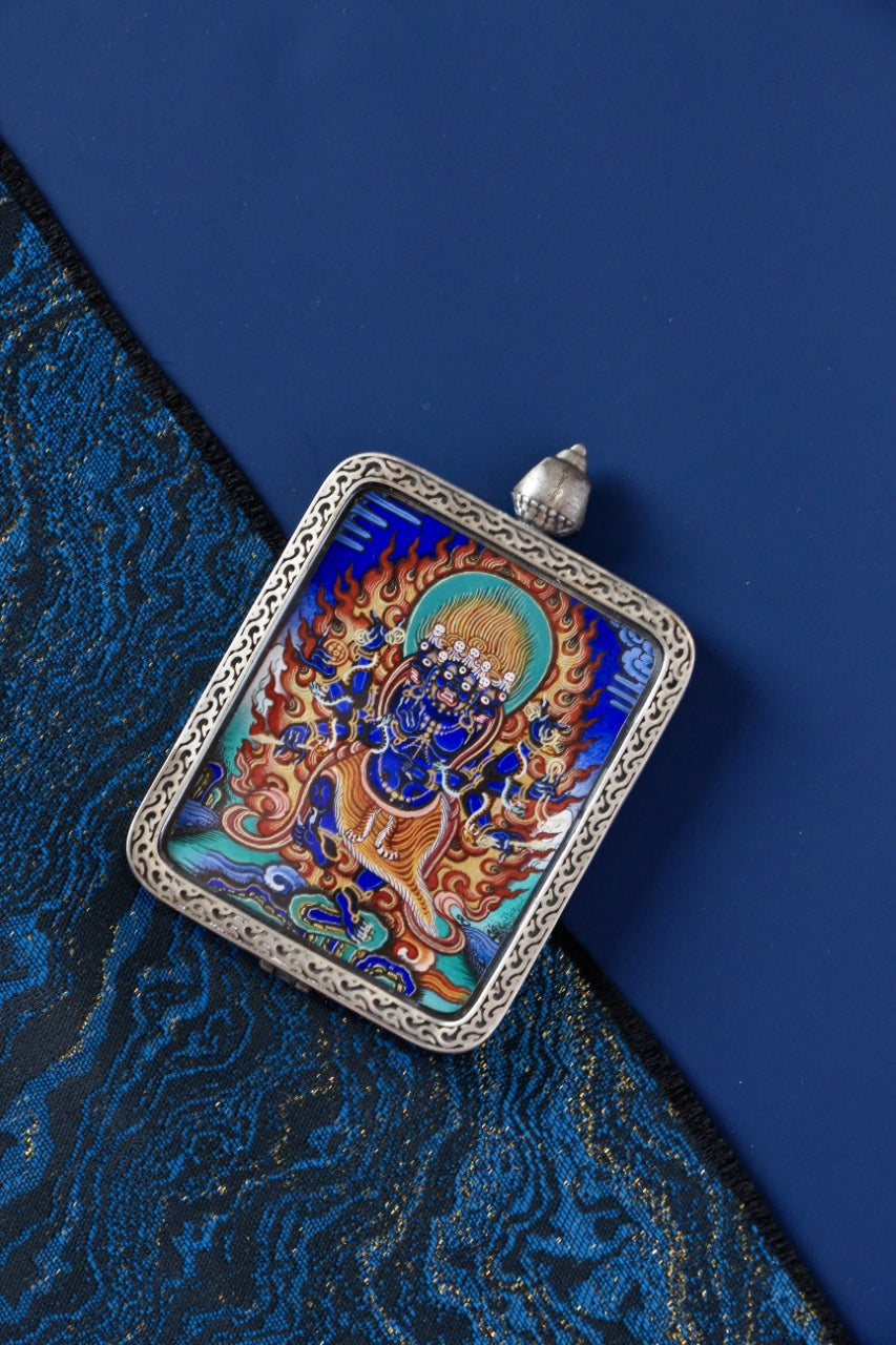Angled view of the Ucchusma Vajra mini thangka pendant, showing vivid mineral pigment colors and the traditional gawu frame.