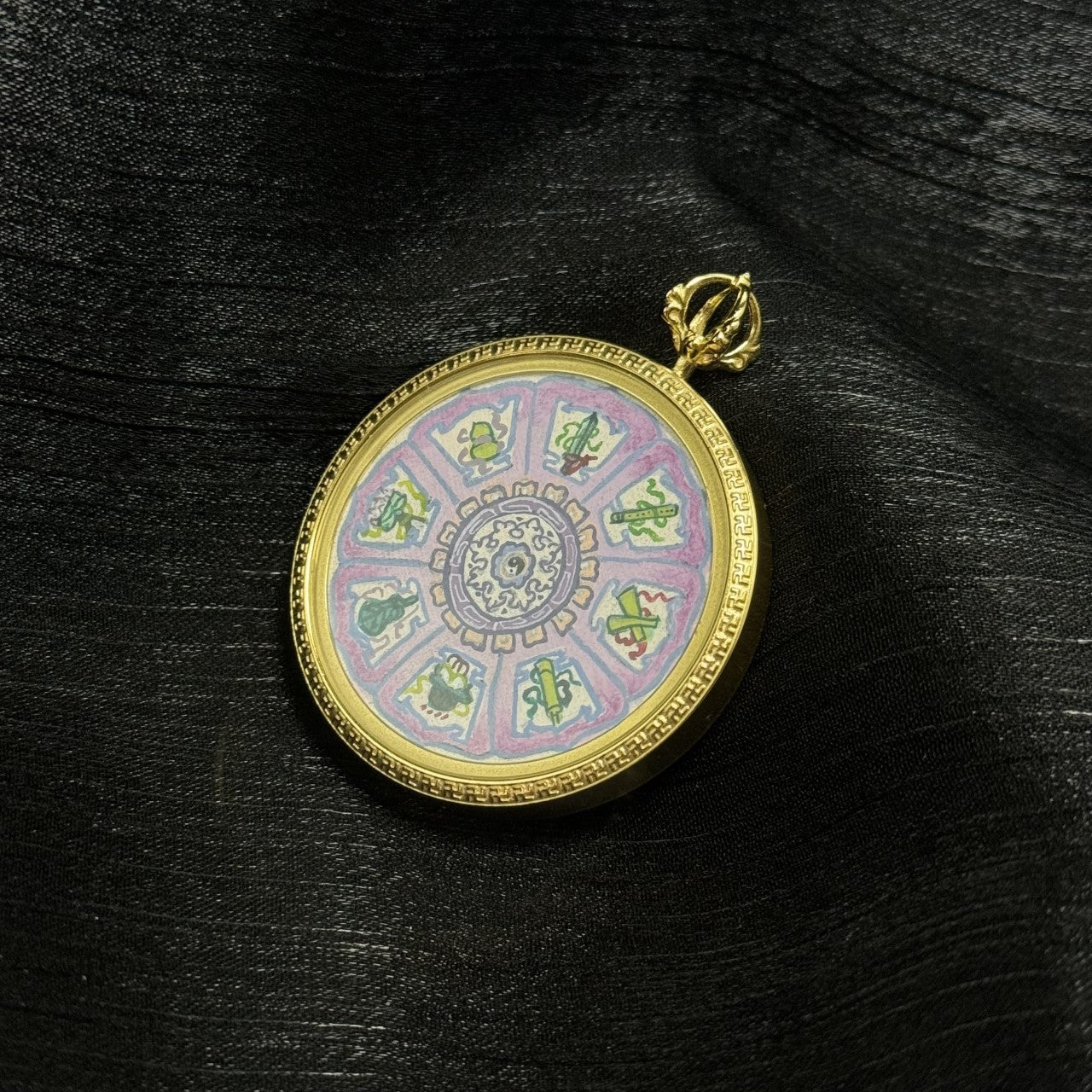 Angled view of an Eight Immortals instruments Bagua mini thangka pendant showing the side thickness, top hanging loop, and the circular painted design within the metal frame.