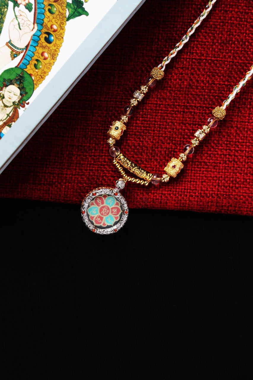 Close-up of Avalokiteshvara mantra mini thangka pendant featuring mineral pigment lotus design and hand-written gold powder mantra inside a jewelry brass case