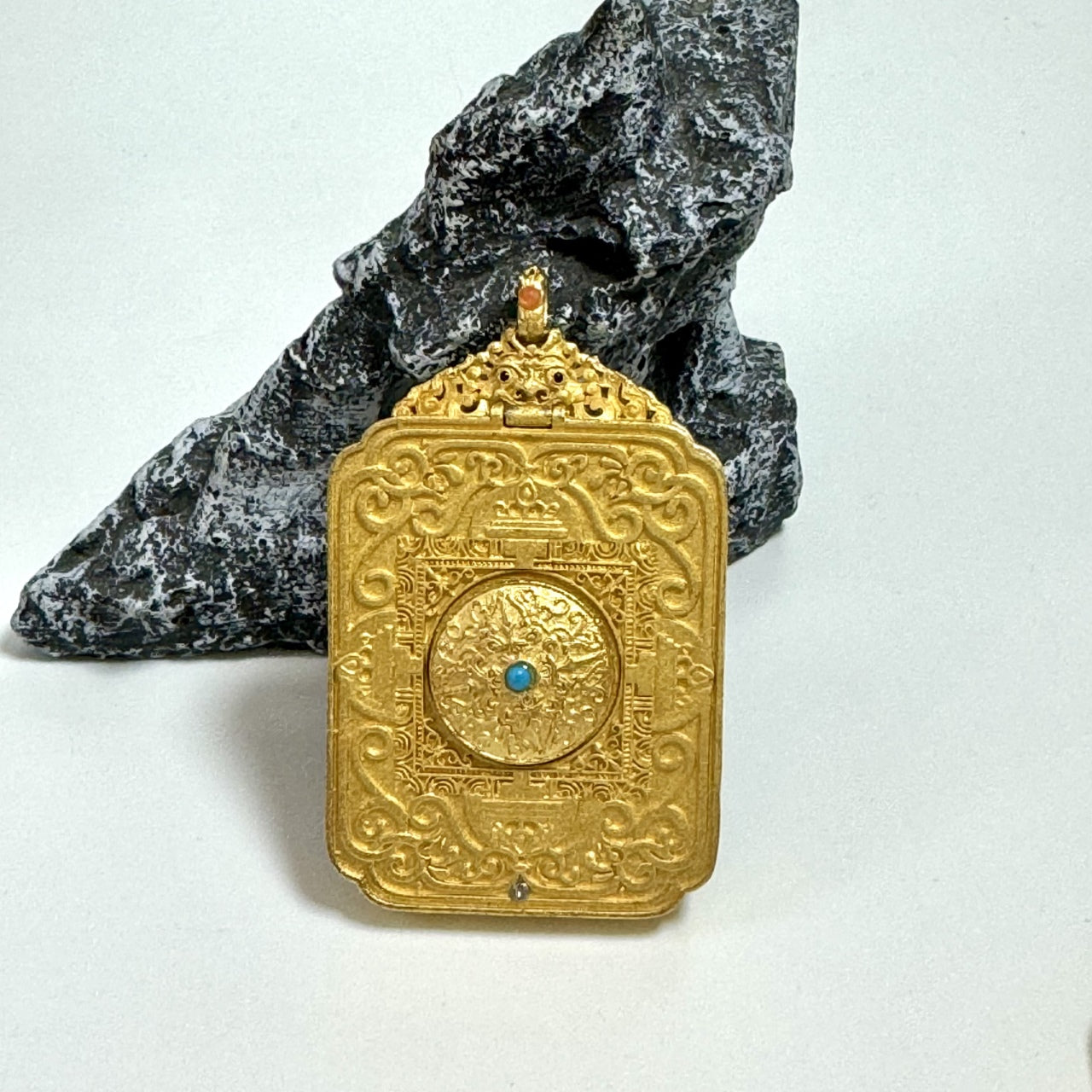 Back view of Manjushri Bodhisattva mini thangka pendant showing engraved copper case, mandala-style pattern, and fine metal craftsmanship