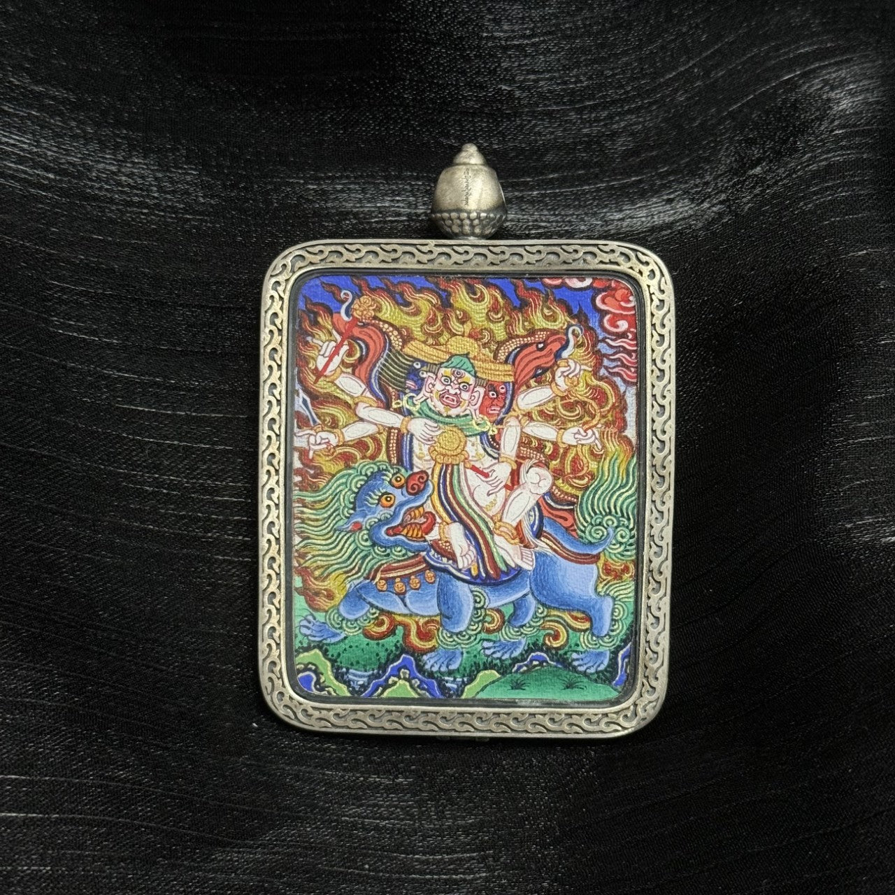 Front view of Baihar mini thangka pendant, hand-painted with mineral pigments in Rebgong style, framed in a silver case with detailed border patterns
