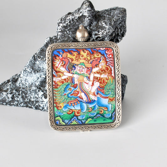 Front view of a hand-painted Baihar (Pehar Gyalpo) mini thangka pendant, featuring dynamic protector deity imagery, layered natural mineral pigments, and a silver gawu-style frame with traditional openwork patterns, painting size 4 × 5 cm.