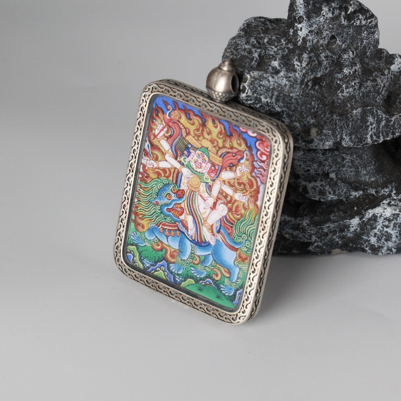 Close view of the Baihar protector deity mini thangka pendant, emphasizing fine hand-painted line work, vivid mineral pigment application, and the traditional silver frame designed for long-term preservation and collection.