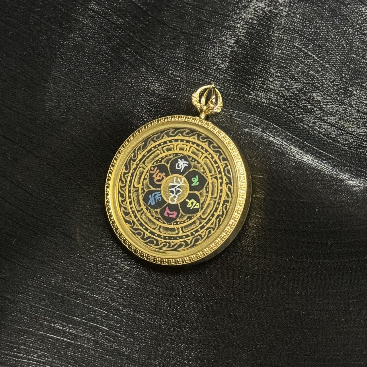 Mini thangka pendant set in titanium steel case, circular gold-tone frame, black background with gold decorative patterns