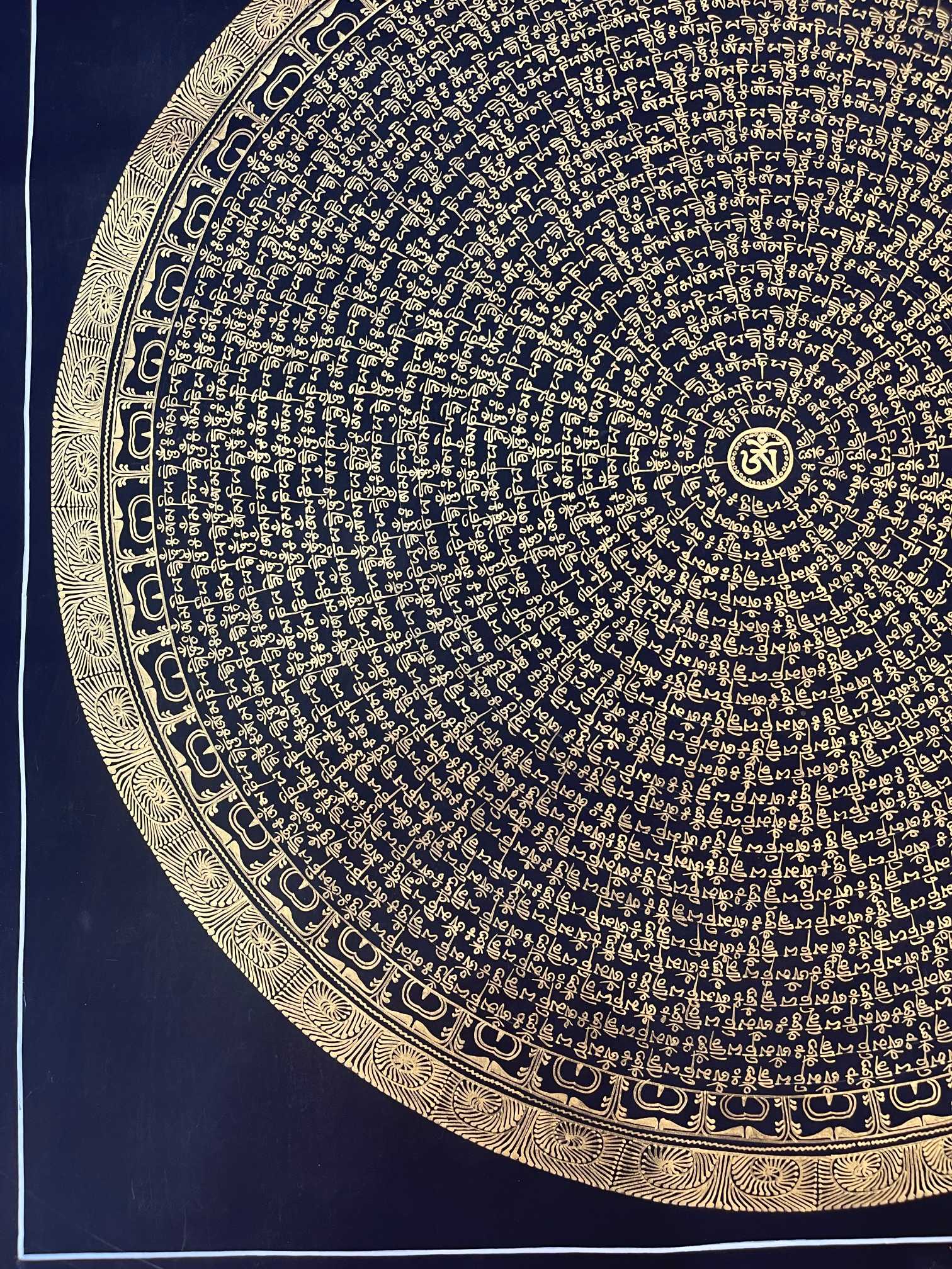 Close-up of the black gold Om Mani Padme Hum thangka showing detailed Tibetan gold calligraphy forming circular mantra rings with decorative outer borders.