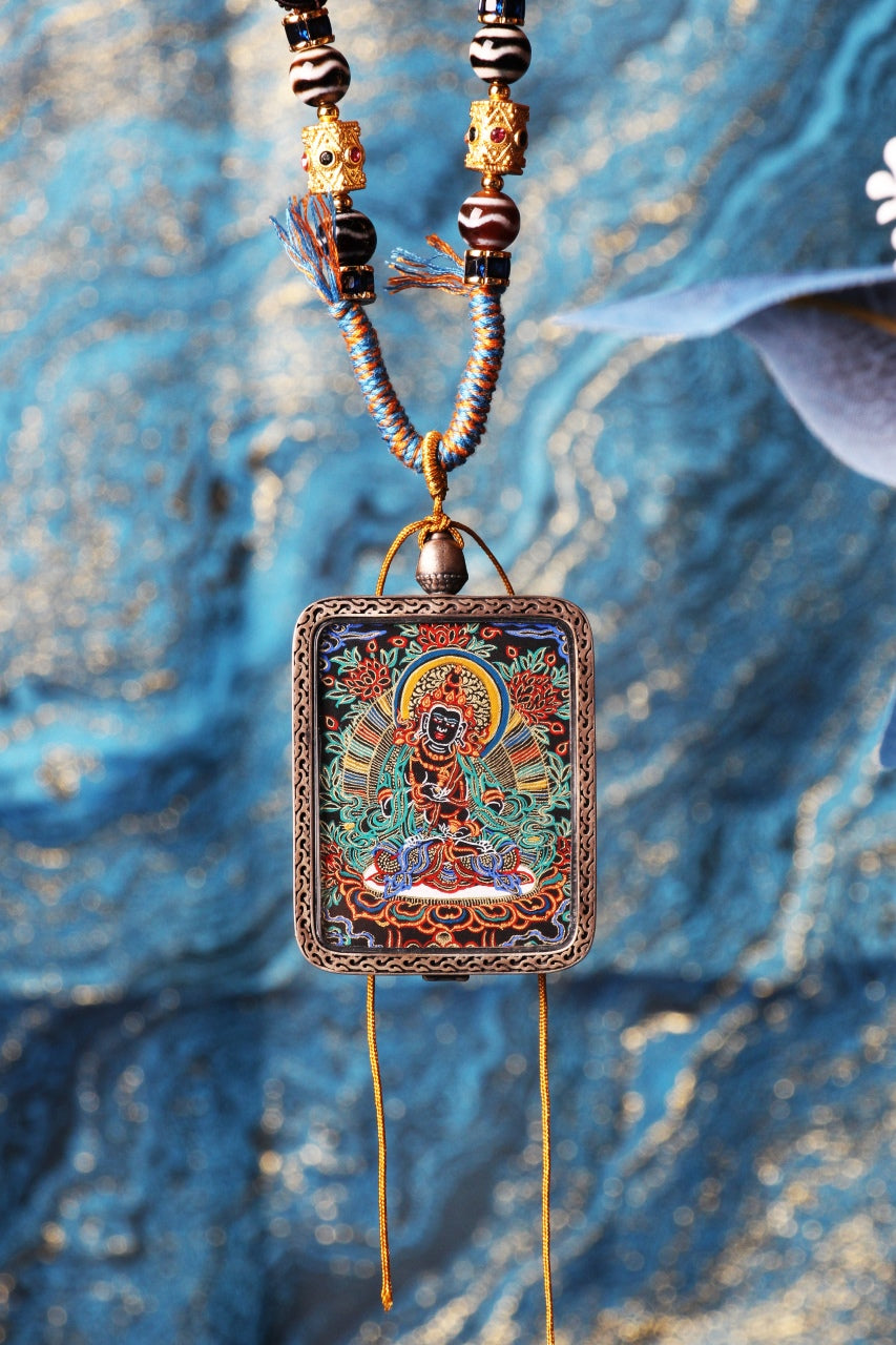 Hanging view of the Vajrasattva pendant necklace featuring black-gold hand-painted thangka art and ornate silver frame on braided cord.