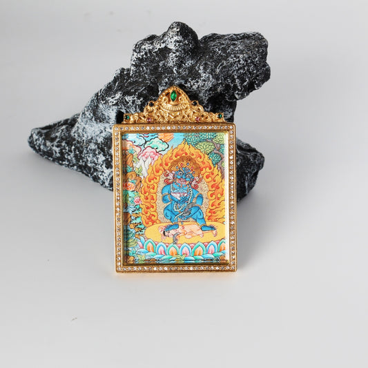 Front view of Black Jambhala mini thangka pendant, hand-painted with mineral pigments, vivid blue figure with flame halo, enclosed in a gold-tone double-sided jewelry-grade titanium steel case with crystal-style border