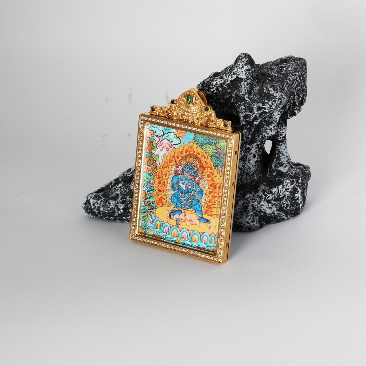 Side detail of Black Jambhala mini thangka pendant highlighting the double-sided construction, metal edge finishing, and refined ornament details on the case