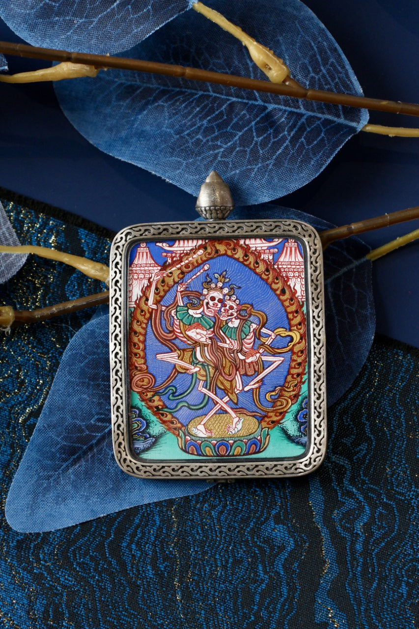 Front view of Chitipati (Cemetery Lord) thangka pendant in a silver case, Regong hand-painted miniature thangka, 4x5cm.