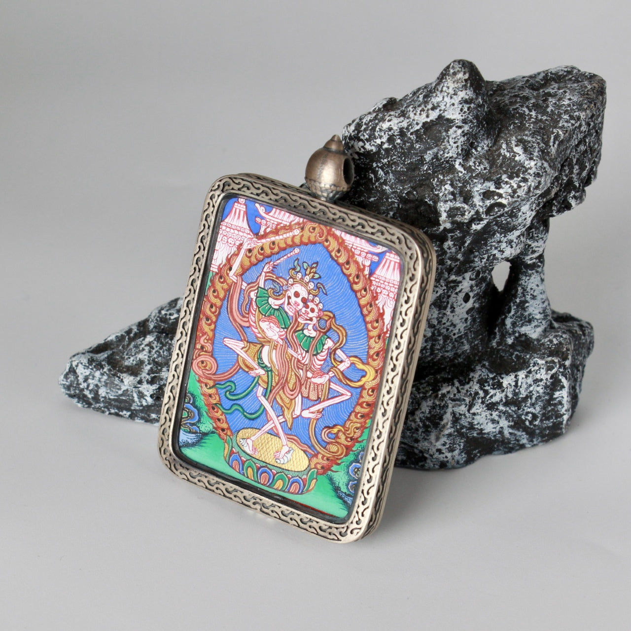 Angled view of the Chitipati thangka pendant emphasizing the depth of the silver gawu frame, hand-painted Rebgong artwork, and protective enclosed structure.