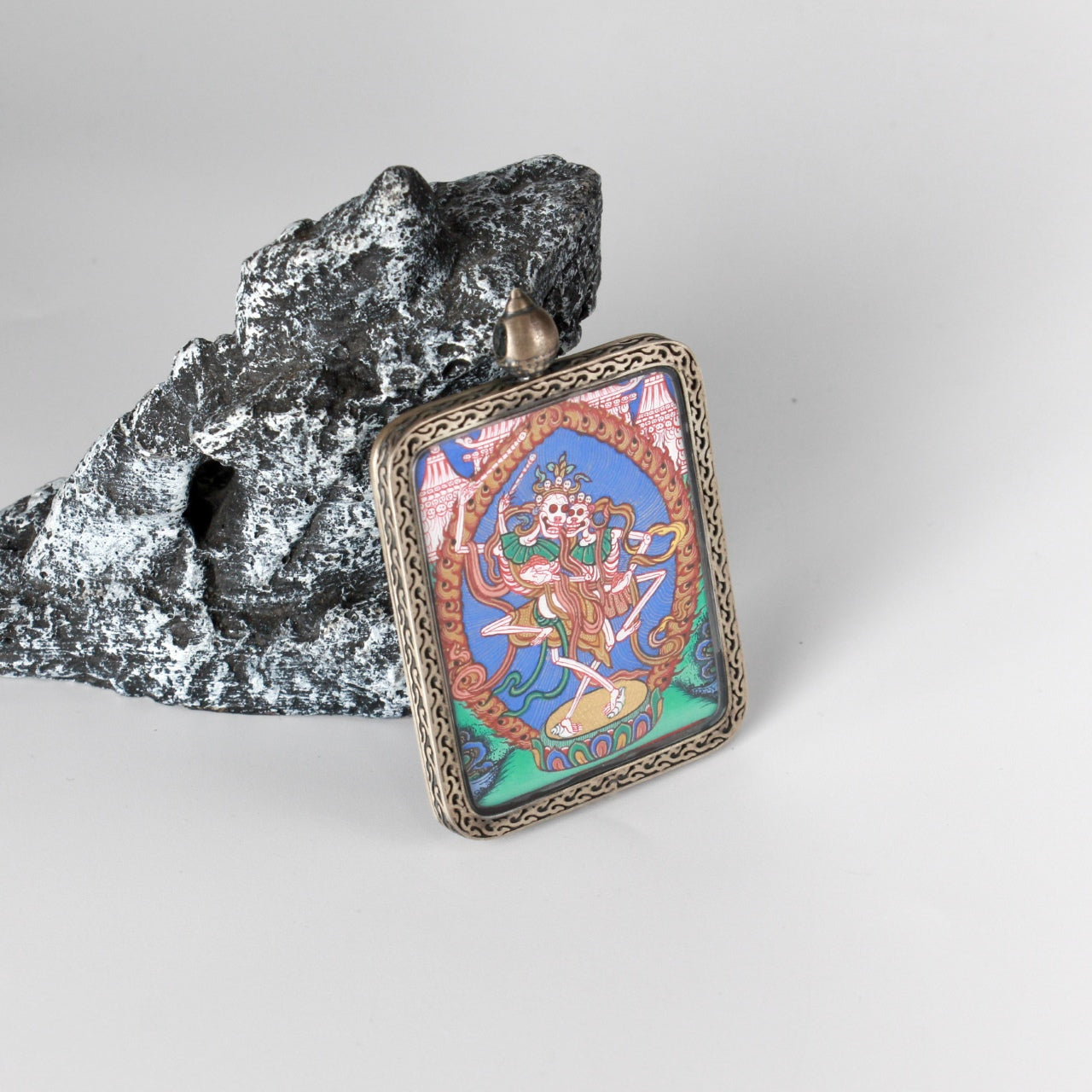 Front view of a hand-painted Chitipati (Lord of the Charnel Ground) thangka pendant, created in the Rebgong tradition with vivid mineral pigments, set in a silver gawu-style case.