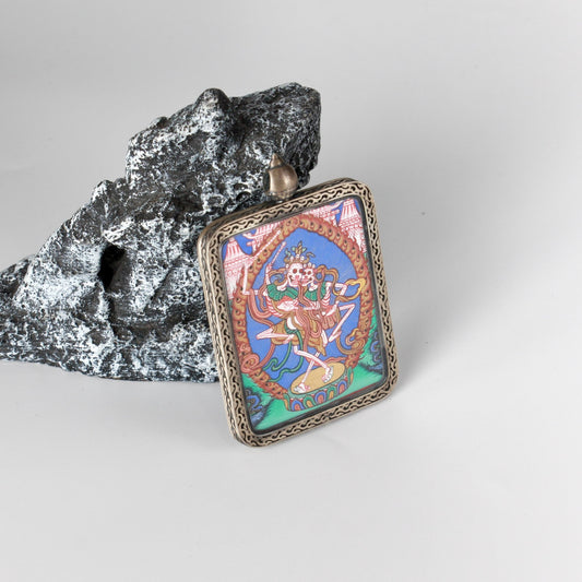 Front view of a hand-painted Chitipati (Lord of the Charnel Ground) thangka pendant, created in the Rebgong tradition with vivid mineral pigments, set in a silver gawu-style case.