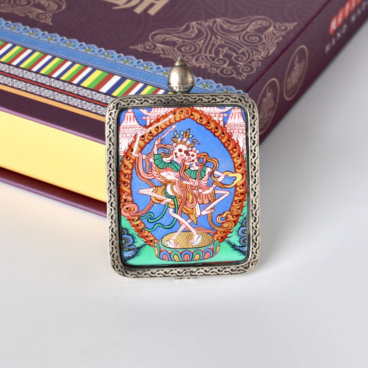 Straight-on view of the Chitipati thangka pendant highlighting the dancing skeletal figures, intricate line work, and layered mineral pigment colors typical of Rebgong thangka painting.
