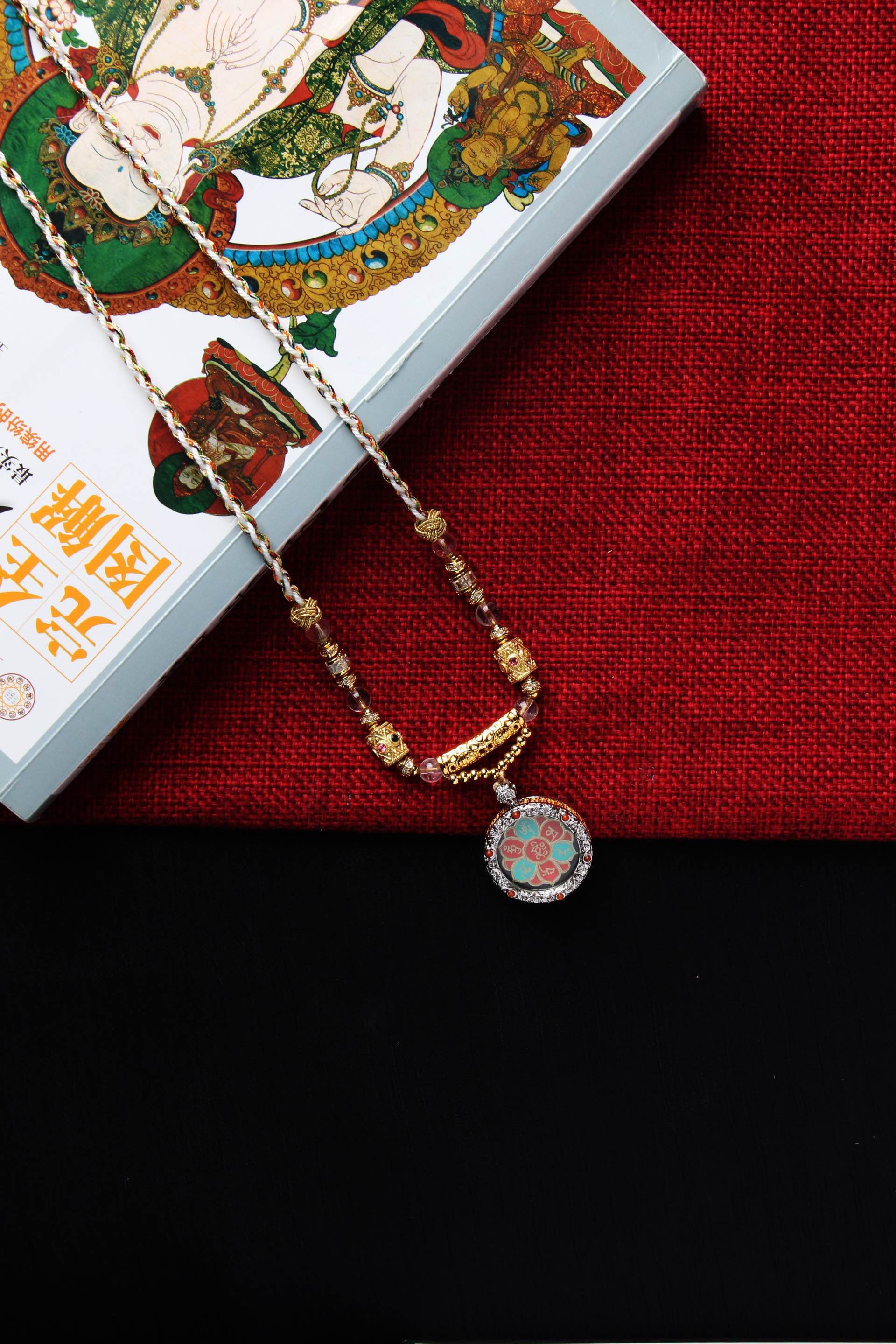 Detailed craftsmanship view of Avalokiteshvara mantra mini thangka pendant highlighting mineral pigment layers, gold powder script, and pendant structure