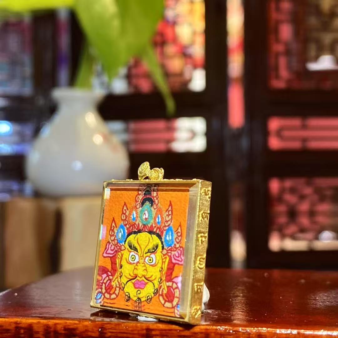 Side view of double-sided mini Thangka pendant showing 18K gold Gau box and sapphire crystal glass
