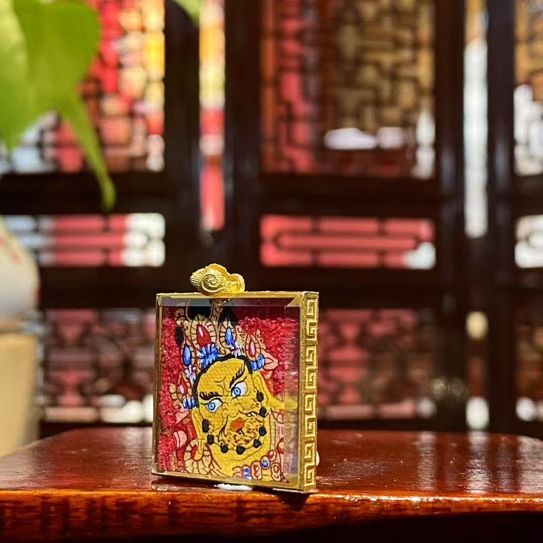 Side view of a double-sided hand-painted Yellow Jambhala mini Thangka pendant, showing the 18K gold Gau box thickness and sapphire crystal glass