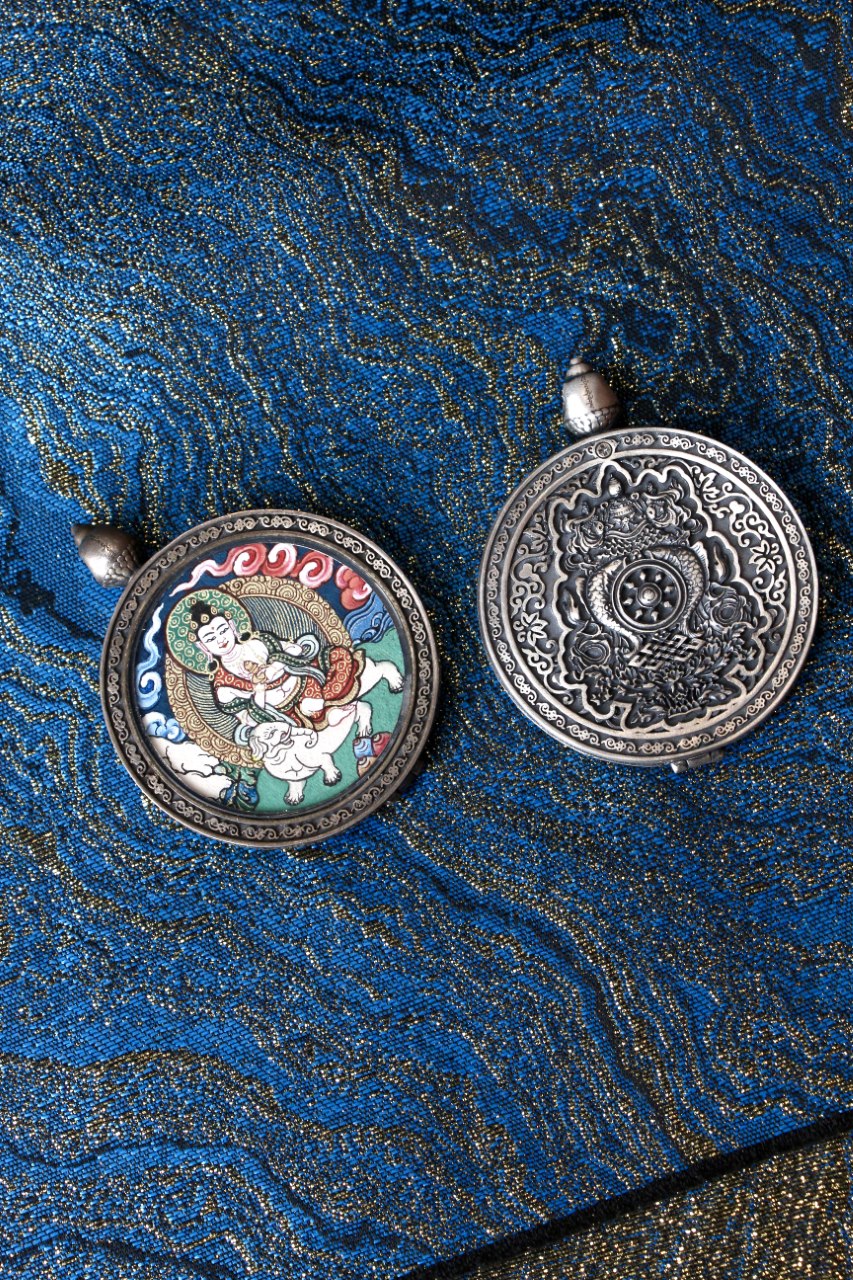 Front and back view of a Samantabhadra Bodhisattva thangka pendant, showing the hand-painted deity image on the front and an engraved silver ornamental design on the back