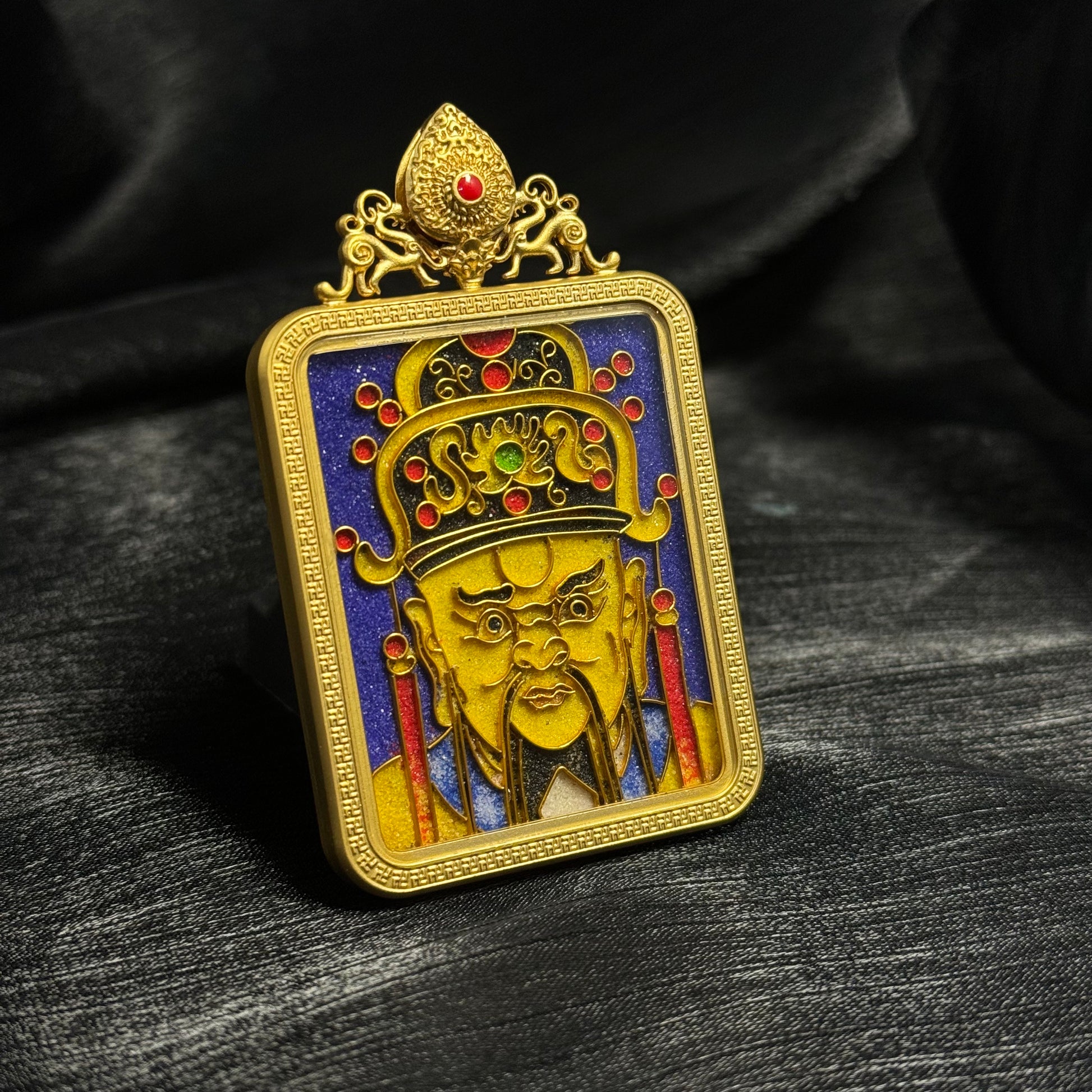 Side perspective of handcrafted Dragon King Wuye mini thangka pendant featuring gold-plated copper casing, cloisonné enamel deity portrait, decorative crown, and vivid blue enamel background.